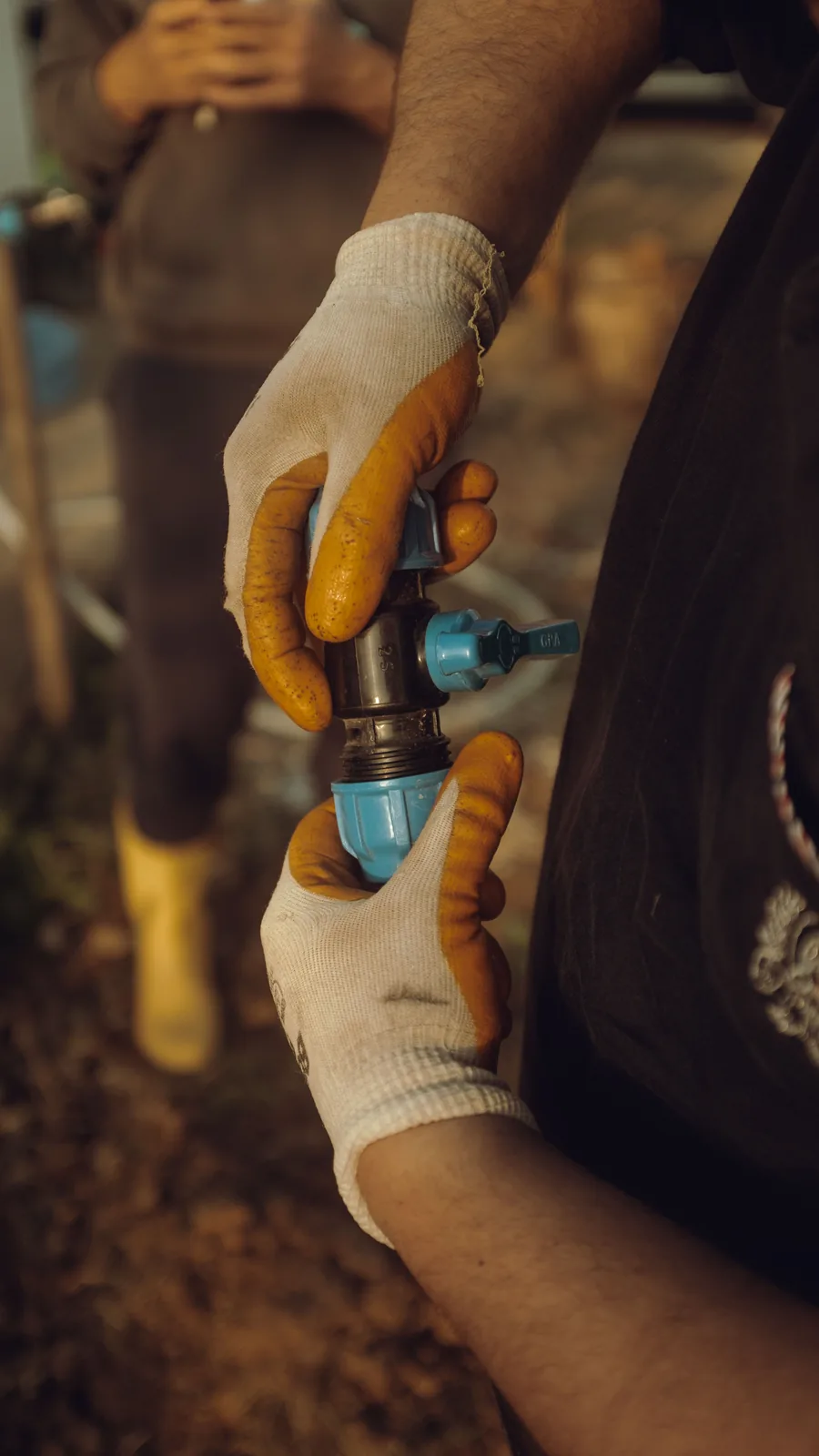 Gloved hands joining a compression fitting on a buried line