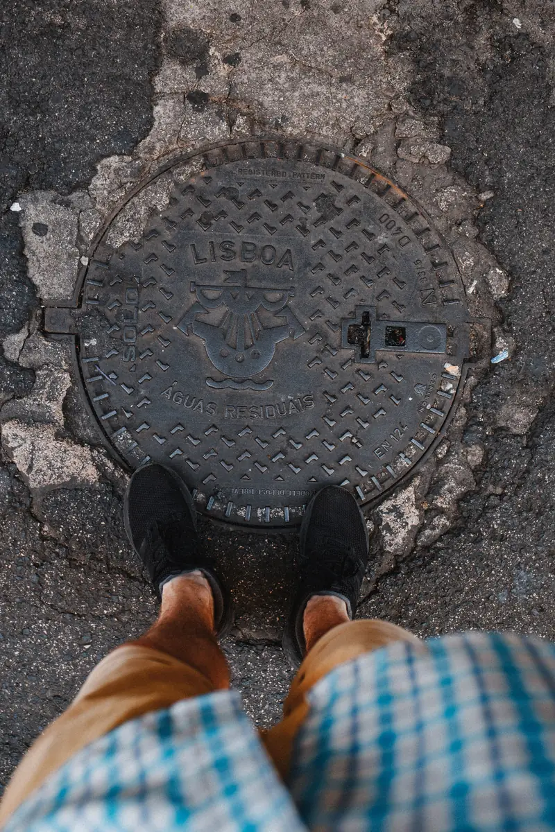 Standing over a cast iron wastewater access cover in the street